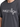 Gray t-shirt featuring bold white text and star graphics, worn by a person from the chest up.