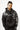 A man wearing a black hoodie with intricate white coral-like designs on the sleeves and a front pocket.