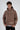 A model wearing a brown hoodie with motivational text, featuring a front pocket and relaxed fit.