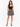 A woman stands confidently in a black crop top and a patterned mini skirt, paired with stylish high heels.
