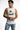 A man wearing a sleeveless white top with a graphic print and distressed denim shorts, posing thoughtfully.