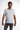 A man wearing a fitted white short-sleeve shirt paired with gray distressed jeans, standing against a light background.