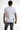 A man is shown from the back wearing a fitted white shirt with gray accents and gray jeans.