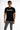 A model wearing a black short-sleeve shirt with a graphic design, paired with distressed gray jeans.