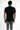 A person wearing a fitted black short-sleeve shirt and gray jeans, viewed from the back against a white background.