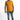 A man stands confidently in a fitted orange shirt paired with distressed blue jeans and white sneakers.