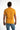 A man wearing a short-sleeve, bright yellow shirt with embossed text on the back, paired with light blue jeans.