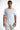 A man wearing a fitted white short-sleeve shirt and distressed white shorts, standing against a plain background.