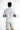 A person wearing a light gray shirt with embroidered text on the back, paired with white shorts featuring colorful pa...