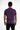 A man stands with his back to the camera, wearing a fitted purple short-sleeve shirt and black jeans.