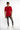 A model wearing a red short-sleeve shirt and distressed gray skinny jeans, paired with white sneakers.