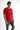A model poses in a fitted red shirt with contrasting black and orange text on the sleeves and hem, paired with distre...