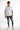 A model stands confidently in a fitted white shirt with black accents, paired with distressed gray jeans and white sn...