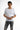 A young man wearing a fitted white t-shirt with graphic text and distressed gray jeans, posing confidently.