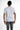 A person wearing a fitted white short-sleeve shirt with contrasting black text on the sleeves and hem.