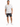 A man stands confidently wearing a short-sleeve patterned shirt, black denim shorts, and white sneakers.