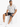A man sits on a white cube wearing a short-sleeve patterned shirt, dark shorts, and white sneakers.