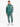 A man stands wearing a teal hoodie and matching joggers with a leaf pattern, paired with white sneakers.