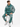 A man sits on a stool wearing a teal sweatshirt with a coral-like design and matching joggers.