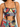 Colorful two-piece set featuring a cropped top with a ruched design and adjustable ties, paired with patterned bottoms.