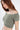 A model showcases a soft, off-the-shoulder, cropped top in a muted green hue with short sleeves.