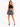 A model poses in a black crochet crop top paired with a patterned skirt and strappy black heels.