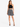 A model wears a black crochet crop top paired with a flowy black and white patterned skirt and strappy heels.
