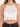 White crochet halter top featuring intricate patterns and a scalloped hem, styled with high-waisted black jeans.