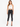 A model poses in a white crochet crop top and black skinny jeans, paired with stylish black heels.