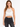 A model wearing a white crochet halter top with a scalloped hem, paired with black high-waisted jeans.