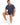 A man sits on a white stool wearing a navy blue top and matching shorts, paired with white sneakers.