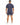 A man stands with his back to the camera, wearing a navy top and matching shorts, paired with white sneakers.