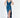 A model poses in a deep blue satin dress with a plunging neckline and a thigh-high slit, paired with black heels.