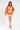 Model in orange The Who graphic sweatshirt and white mini skirt, a trendy knit top for streetwear fashion.