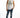 A young man poses in a sleeveless white top with a graphic design, paired with distressed blue jeans and white sneakers.