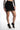 Maddison black high-waisted mini skirt featuring an asymmetrical wrap front and eyelash lace trim at the hem.
