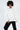 Model in Ari oversized white crewneck sweatshirt with QUstyle patch and black pants against a white background.