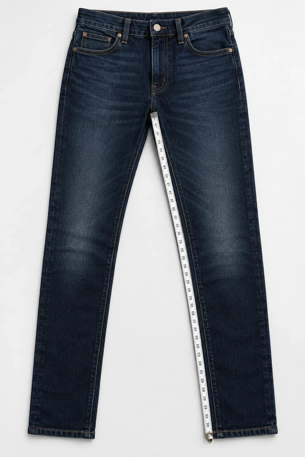 Full pair of jeans laid flat with a measuring tape running from the crotch seam to the bottom hem along the inner leg